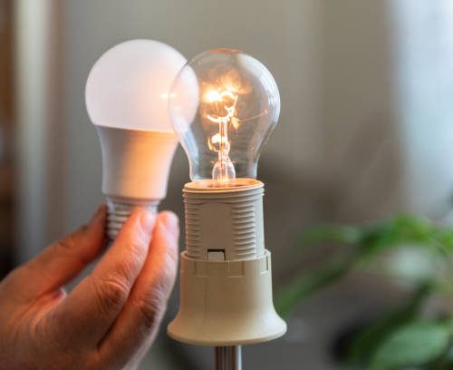 Power saving concept.Man changing compact-fluorescent (CFL) bulb with new LED light bulb.
