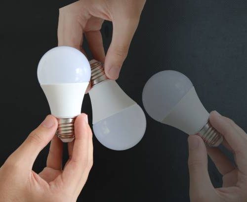 man holding light bulb on black background. electricity and savings