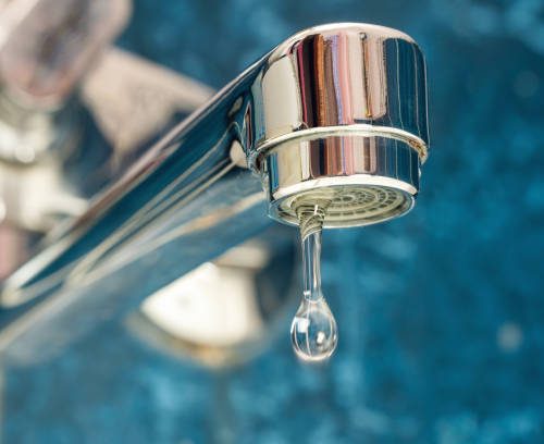 A drop of water drips from a leaky faucet.